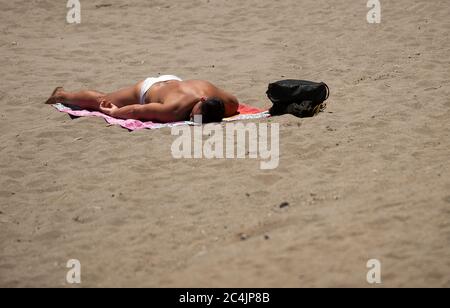 Malaga, Spagna. 27 Giugno 2020. Un uomo che prende il sole sulla spiaggia di la Caleta durante una calda giornata estiva.UN'onda di calore attraversa il paese con alte temperature, secondo l'Agenzia Meteorologica Spagnola. Credit: Jesus Merida/SOPA Images/ZUMA Wire/Alamy Live News Foto Stock