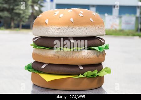 Big hamburger artificiale è fatto con un amore. Si trova in strada come materiale pubblicitario. Primo piano. Foto Stock