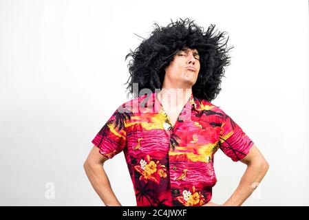 Uomo con parrucca afro e camicia hawaiana, molto sicuro, con un atteggiamento boss. Scatto medio. Sfondo bianco. Foto Stock
