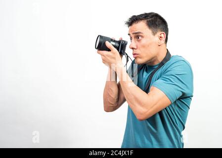 Uomo con macchina fotografica che fotografa qualcosa di molto concentrato, vista laterale. Scatto medio. Sfondo bianco. Foto Stock