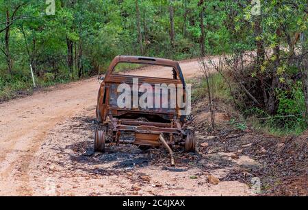 Bruciato il relitto dell'automobile abbandonato sul lato di una pista sterrata nelle montagne Foto Stock