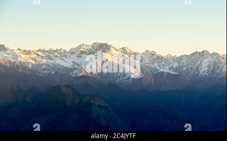 Tonalità dorate del sole di mattina sopra le cime di montagna, catena montuosa di Shivalik, Himalaya- preso da HATU Peak, Narkanda, Himachal Pradesh Foto Stock