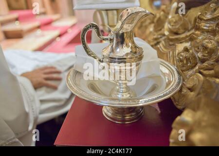 Lavabo liturgico e caraffa accanto a un sacerdote seduto. Caraffa e manico decorati con elementi in rilievo Foto Stock