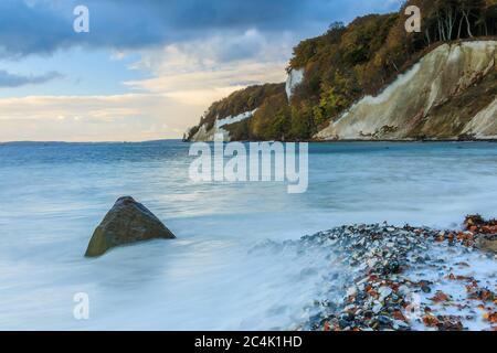 Isola Ruegen con scogliere di gesso nel Parco Nazionale di Jasmund al mattino con costa sassosa. Baia dei pirati in autunno umore con alberi decidui e nuvole Foto Stock