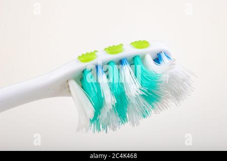 Spazzolino da denti su un tavolo bianco. Setole molto usurate in una spazzola per l'igiene personale. Sfondo chiaro. Foto Stock