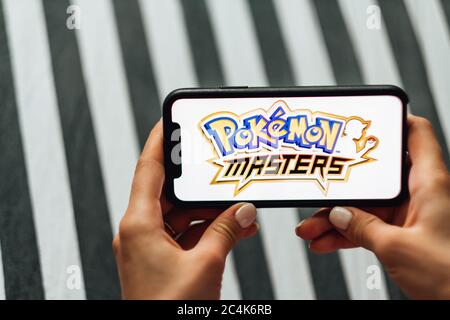 Mani che tengono iPhone con i maestri Pokemon sullo schermo. Foto Stock