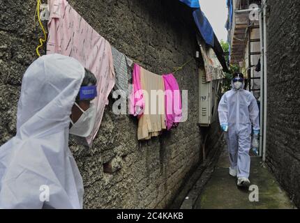 Gli operatori sanitari che indossano tute protettive camminano attraverso la colonia di slum per schermare le persone per pandemia di coronavirus.i casi di Coronavirus sono raddoppiati in una delle colonie di slum densamente popolate con una popolazione di oltre due lakh nel sobborgo settentrionale di Mumbai. Entro giorni dalla sblocco 1.0, è stato completamente sigillato per cinque giorni per frenare l'ulteriore diffusione del virus. Foto Stock