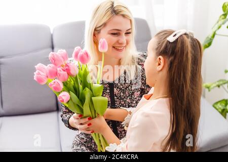 Buon giorno della madre. La figlia del bambino si congratula con le mamme e dà i suoi tulipani di fiori Foto Stock