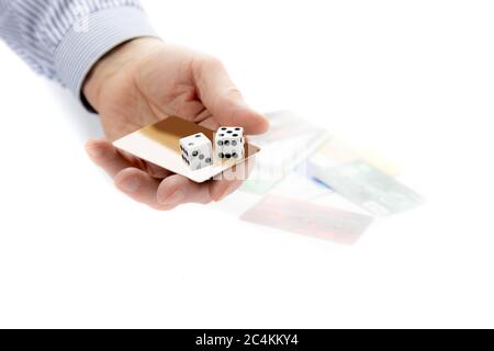 una mano dell'uomo tiene un paio di dadi gioco d'azzardo con una carta di credito non identificata con altre carte di credito in background isolato su bianco Foto Stock