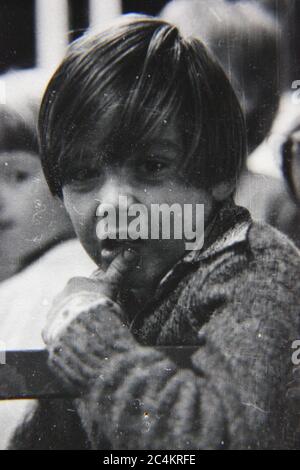 Fine anni '70 vintage nero e bianco stile di vita fotografia di un ragazzo stanco in attesa di un suo turno in un giro al carnevale di tarda notte. Foto Stock