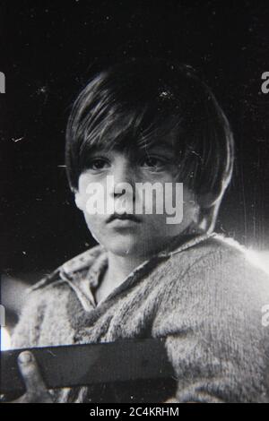 Fine anni '70 vintage nero e bianco stile di vita fotografia di un ragazzo stanco in attesa di un suo turno in un giro al carnevale di tarda notte. Foto Stock