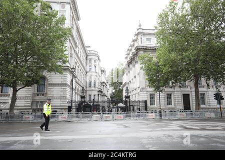 Londra, Regno Unito. 27 Giugno 2020. Un poliziotto cammina lungo Whitehall con Downing Street sullo sfondo, poiché le barriere sono già state messe in atto in caso di problemi che possono derivare da una qualsiasi delle proteste e raduni di oggi a Londra. Credit: Paul Marriott/Alamy Live News Foto Stock