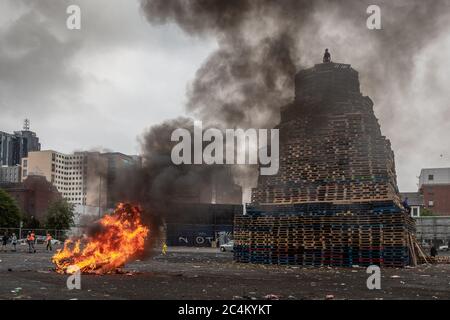 Un uomo in piedi in cima a un falò Sandy Row, Belfast prima delle undicesima festa notturna che iniziano a mezzanotte. Foto Stock