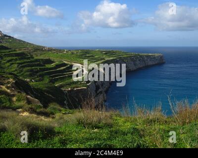 FOMM IR-RIH, RABAT, MALTA - 09 febbraio 2014: Una vista panoramica della baia di fomm ir-Rih e delle scogliere costiere di Malta, con il mare blu, il cielo nuvoloso e l'orizzonte. Foto Stock