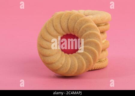 primo piano una pila di biscotti cremosi alla frutta di fragola isolati su rosa Foto Stock