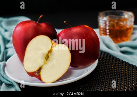 Due mele e una terza tagliata a metà su un piatto bianco. Foto Stock