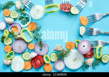 Anelli di cipolla su sfondo blu. Cipolla biologica fresca, aglio e peperone, sedano, verdure aneto con spazio per la copia. Sfondo vegetariano Foto Stock