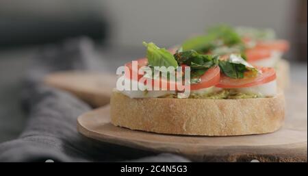 bruschetta con pomodoro, pesto e mozzarella su tavola d'oliva Foto Stock