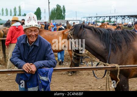 Mercato animale a Karakol, Kirghizistan. Uomo che mostra i denti. Foto Stock