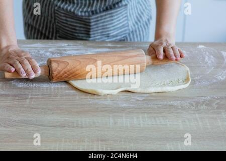 stendere la pasta di lievito con un rullo di pasta di legno Foto Stock
