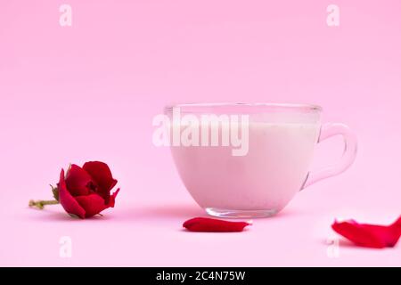 Latte di luna rosa da letto in una tazza di vetro su sfondo rosa pastello con spazio per il testo Foto Stock