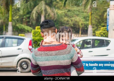 Ritratto di maliziosa bambina indiana nelle braccia del padre all'aperto. Foto Stock