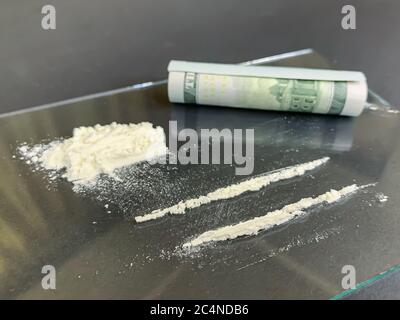 Primo piano di 100 dollari e 2 linee di cocaina su sfondo grigio. Tossicodipendenza illegale. Immagine stock. Foto Stock