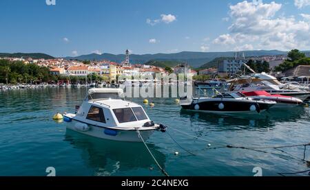 Crikvenica fronte mare e porto. Molte barche e yacht sono ormeggiati nel porto di fronte alla città con le montagne Dinariche sullo sfondo. Foto Stock