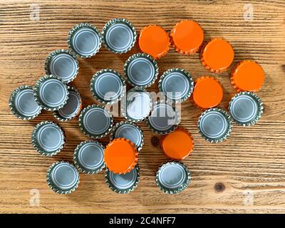 Molti coperchi di birra arancione, tappi per bottiglie su una texture di legno vista dall'alto immagine orizzontale Foto Stock