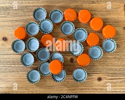 Molti coperchi di birra arancione, tappi per bottiglie su una texture di legno vista dall'alto immagine orizzontale Foto Stock