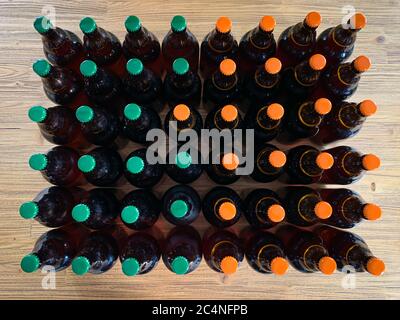 Un sacco di birra fatta in casa propria birreria. Molte bottiglie di birra artigianali in vetro marrone con tappi verdi e arancioni, vista dall'alto piatta su un im orizzontale in legno Foto Stock