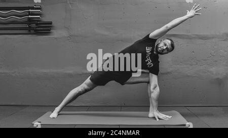 Giovane uomo sportivo che lavora fuori, facendo yoga del handstand. Studio girato in palestra urbana fitness con sfondo grigio per spazio copia. Foto Stock