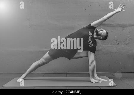 Giovane uomo sportivo che lavora fuori, facendo yoga del handstand. Studio girato in palestra urbana fitness con sfondo grigio per spazio copia. Foto Stock