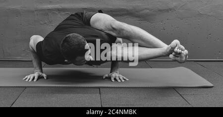 Giovane uomo sportivo che lavora fuori, facendo yoga del handstand. Studio girato in palestra urbana fitness con sfondo grigio per spazio copia. Foto Stock