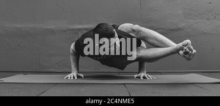 Giovane uomo sportivo che lavora fuori, facendo yoga del handstand. Studio girato in palestra urbana fitness con sfondo grigio per spazio copia. Foto Stock