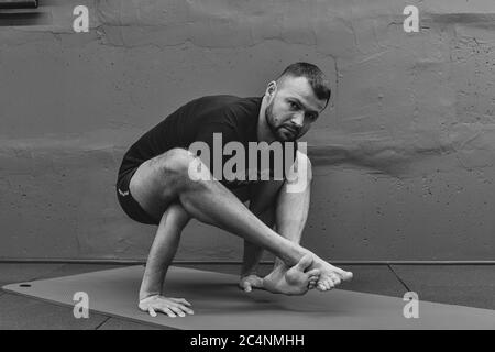 Giovane uomo sportivo che lavora fuori, facendo yoga del handstand. Studio girato in palestra urbana fitness con sfondo grigio per spazio copia. Foto Stock