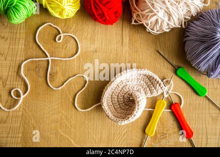 Alto angelo colpo di progetto di maglia incompleto con aghi a gancio su tavolo di legno Foto Stock