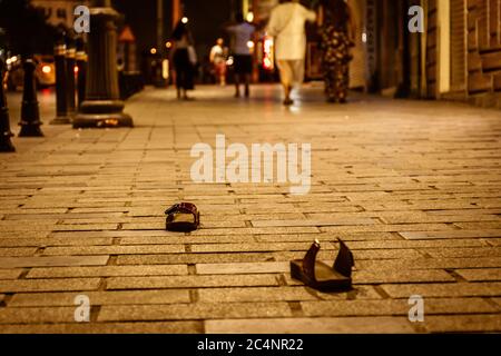 un paio di pantofole da strada strappate e abbandonate per le donne si alza in piedi drammaticamente alla caduta. Foto Stock