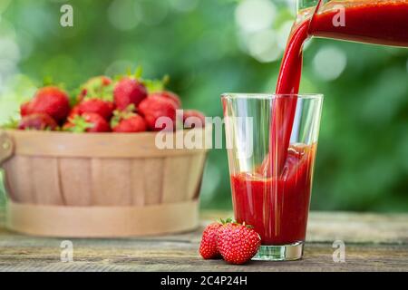 frullato di fragola che si versa in vetro Foto Stock