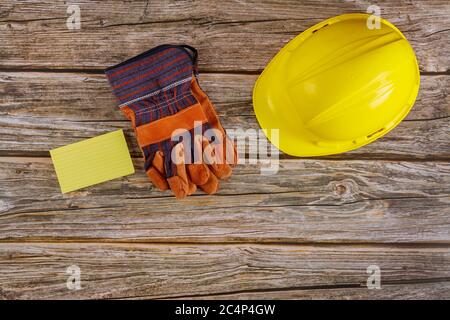 Attrezzatura di sicurezza standard per la costruzione sul casco di sicurezza per guanti protettivi di sicurezza da lavoro su sfondo di legno. Foto Stock