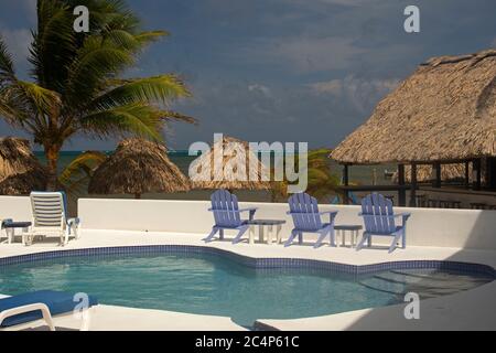 Sedie a sdraio e piscina in un resort sul lungomare, San Pedro, Ambergris Caye, Belize Foto Stock