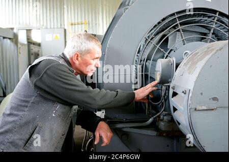 Operatore che controlla il livello di pressione dell'aria su un manometro di un impianto di raffreddamento Foto Stock