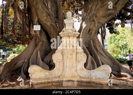 València, Comunidad Valenciana, Spagna. Giardini Glorieta (Jardins de la Glorieta o Jardines de la Glorieta) vicino a Plaza de la porta de la Mar. Monumento dedicato al pittore spagnolo Antonio Muñoz Degrain sotto un albero monumentale Ficus macrophylla. Foto Stock
