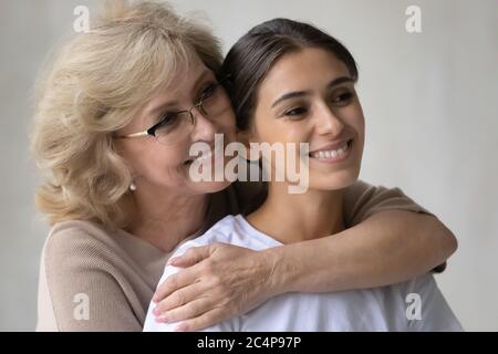 Primo piano felice madre matura abbracciare figlia adulta dalla schiena Foto Stock