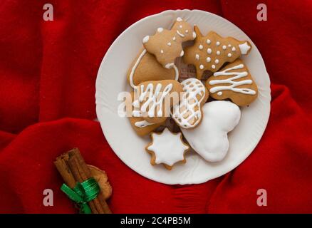 Biscotti natalizi smaltati di forma diversa. Fuoco albero pan di zenzero, cuore forma pan di zenzero e orsacchiotto pan di zenzero con sfondo rosso. Foto Stock