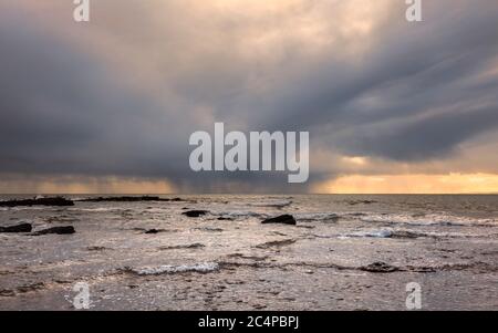 Una tempesta invernale retroilluminata in mare sulla costa inglese Foto Stock