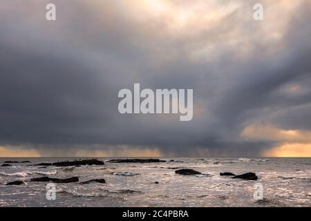 Una tempesta invernale retroilluminata in mare sulla costa inglese Foto Stock