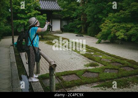 Una signora locale scatta foto del giardino del tempio il 28 giugno 2020 a Kyoto, Giappone. Il numero di visitatori stranieri in Giappone è sceso del 99.9% rispetto allo scorso anno e le restrizioni globali sui viaggi limitano severamente il trasporto internazionale di passeggeri in mezzo alla pandemia del coronavirus Covid-19. 28 giugno 2020 Credit: Nicolas Datiche/AFLO/Alamy Live News Foto Stock