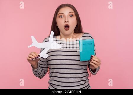 WOW, sto andando in viaggio! Ritratto di stupito bella giovane donna che tiene passaporto e aereo di carta, guardando la macchina fotografica con sorpresa espressione, Sho Foto Stock