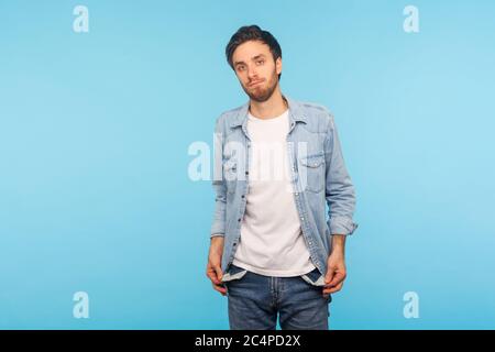 Ritratto di un povero frustrato di camicia in denim lavoratore che mostra tasche vuote, senza soldi, che soffre la depressione nella crisi finanziaria, problemi di debito. Foto Stock